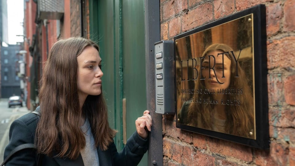 Katharine betrachtet ein Schild, das am Eingang der Anwaltskanzlei «Liberty» angebracht ist.