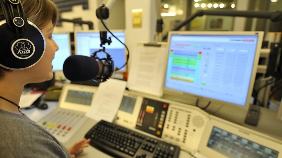 Radio-Moderatorin sitzt am Pult mit vielen Bildschirmen und vor ihr ein Mikrophon