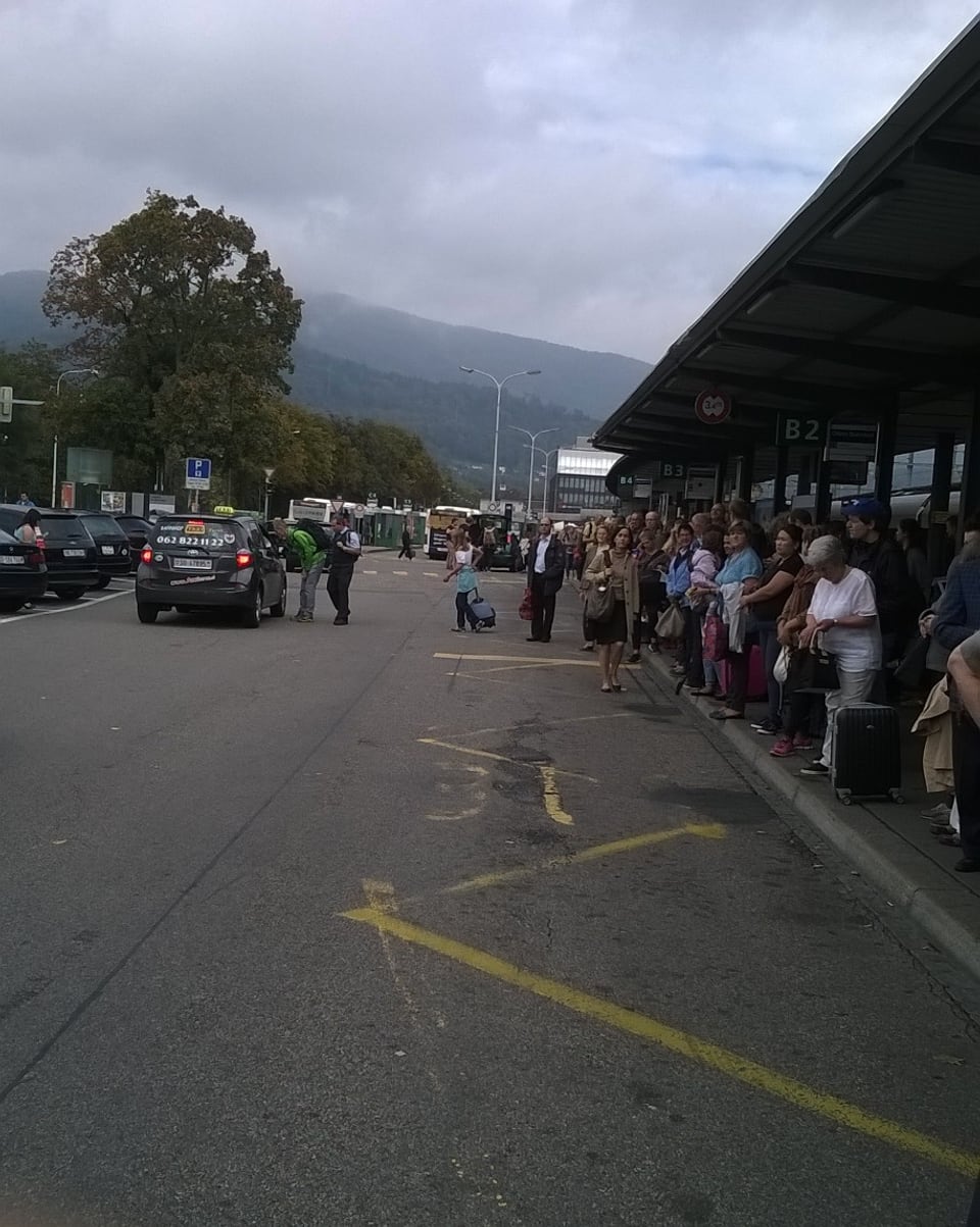Leute warten an einer Busstation.