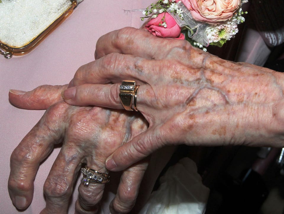 Zwei Hände alter Frauen mit Eheringen an den Fingern.