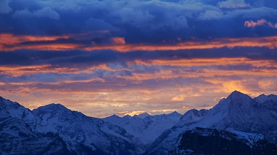 Leicht rötlich gefärbte Wolken über Alpen