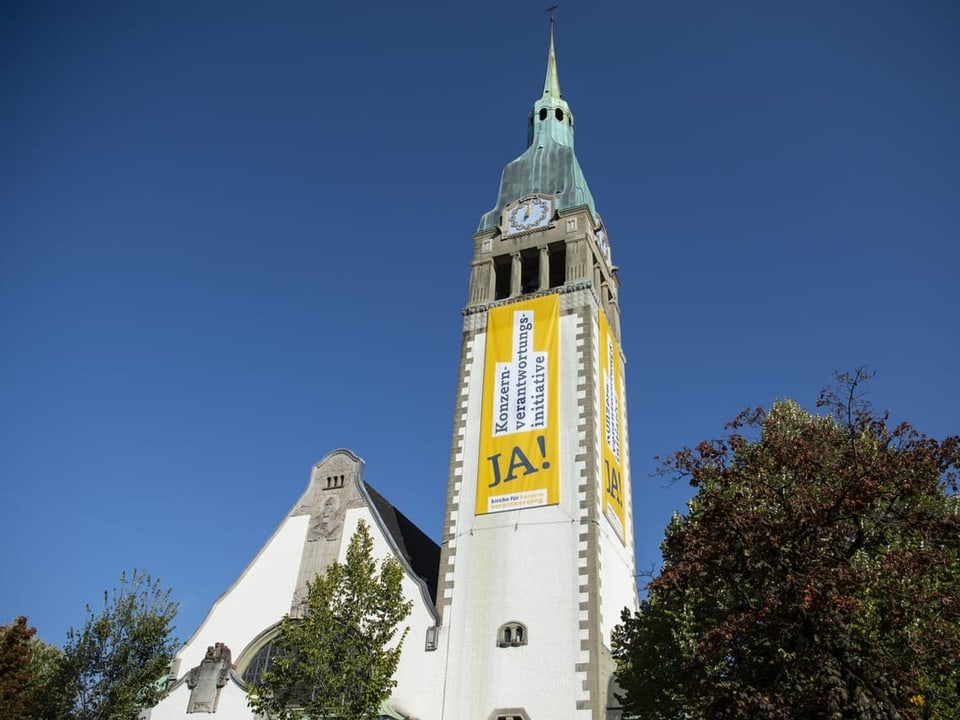 Übergrosse gelbe Banner zur Konzernverantwortungsinitiative hängen am Turm der reformierten Pauluskirche in Bern.