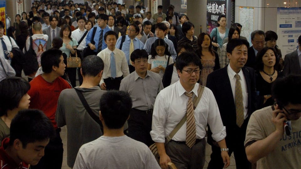 Menschen gehen durch die Gänge der U-Bahn in Tokio.