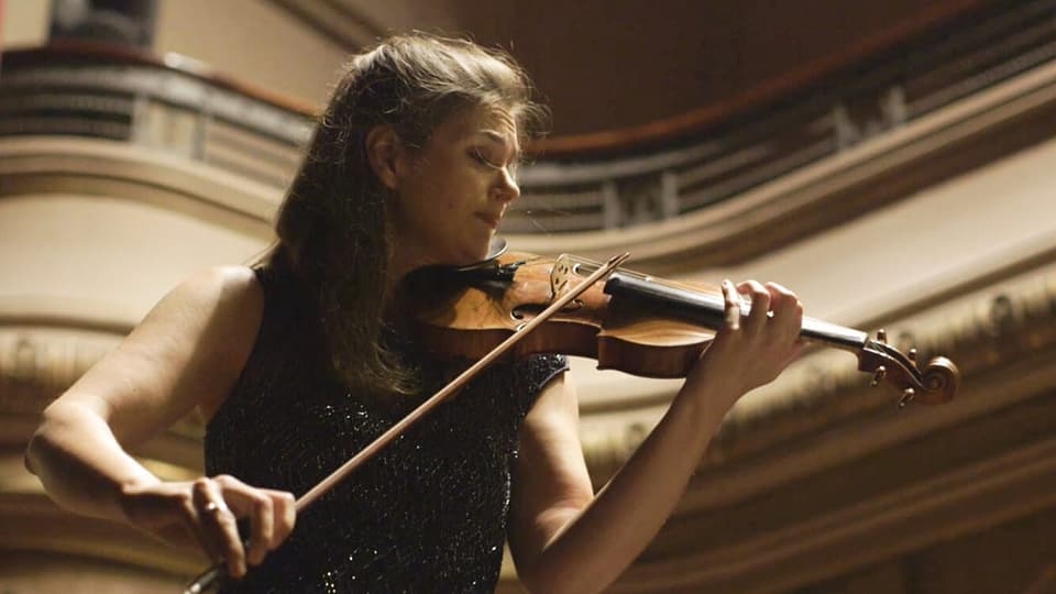 Eine Violinistin spielt in einem Konzerthaus auf der Bühne.