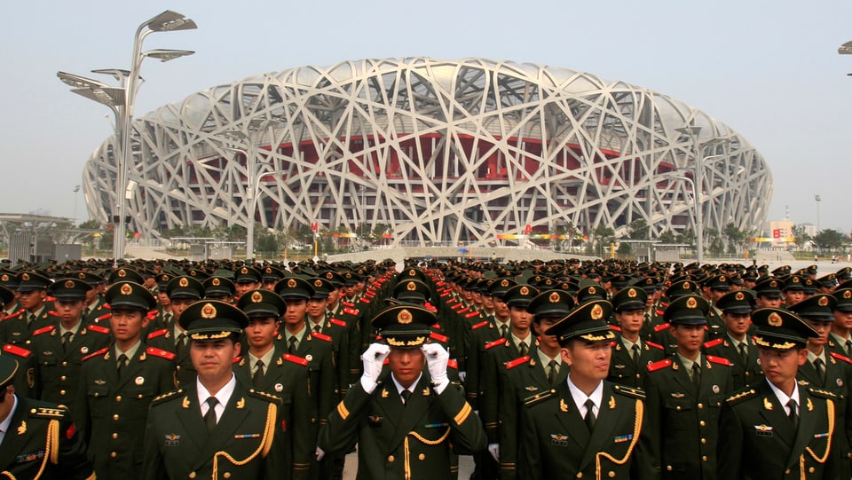 Eine Aussenaufnahme des Stadions in Peking, davor eine Militärparade.