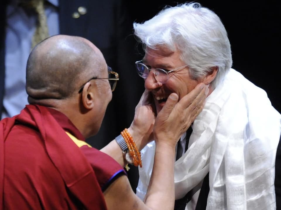 Der Dalai Lama und Richard Gere lachen sich an.