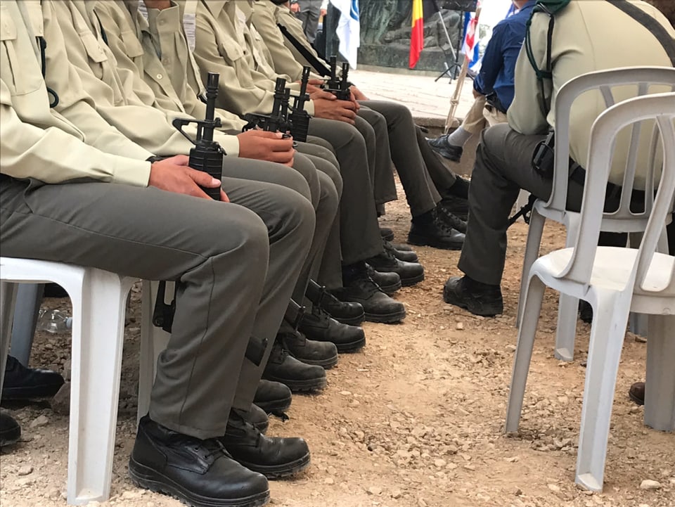 Soldaten mit Waffen sitzen in einer Reihe.