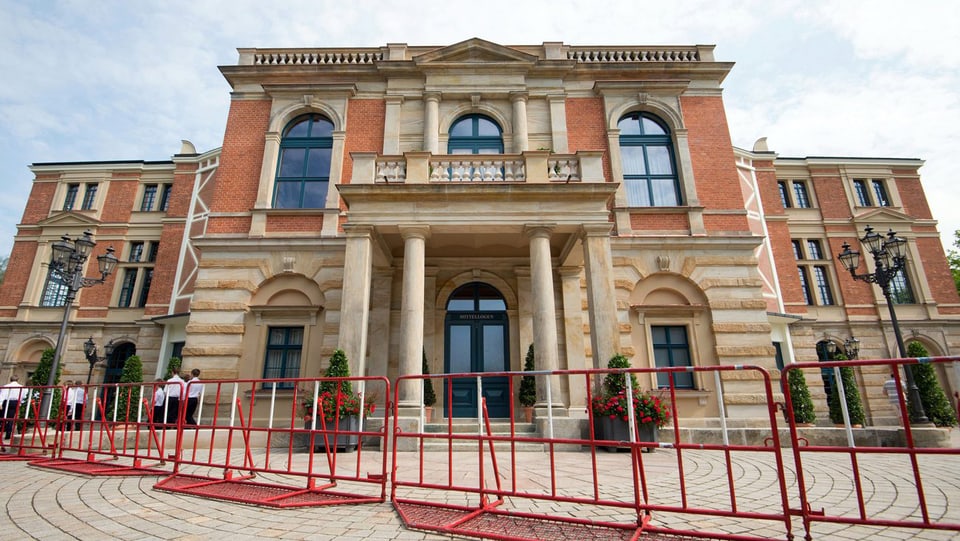 Das kalssizistische Bayreuther Festspielhaus, vor dem rote Abschrankungen auffgebaut sind.