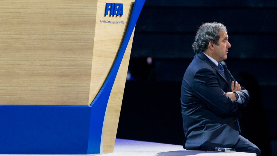 Michel Platini sitzt an einem Fifa-Anlass vor dem Logo des Weltfussballverbandes. 