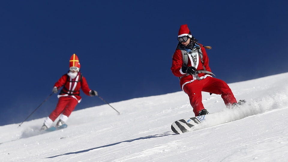 Eine als Samichlaus verkleidete Snowboarderin und ein ebenso verkleideter Skifahrer.