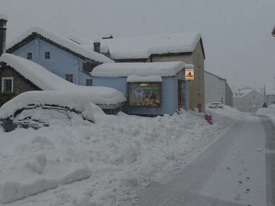 Foto eines Dorfes mit Häusern und viel Neuschnee auf den Dächern und Strassen. Alles ist tief verschneit. 
