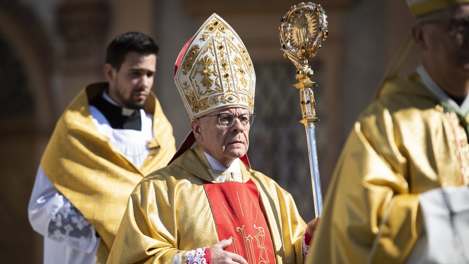 älterer Mann mit Brille im gelb-roten Bischofsgewand mit Bischofshut