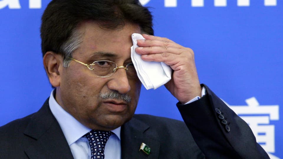 Musharraf tupft sich vor blauem Hintergrund den Schweiss von der Stirn.
