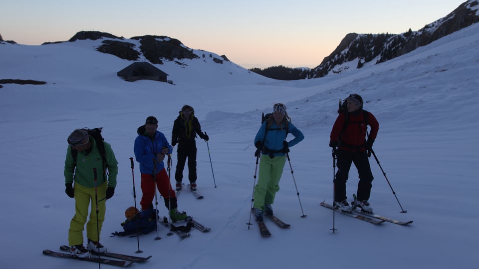 Bergführer mit Gipfelstürmer im Morgenrot im verschneiten Gantrisch-Gebiet. 