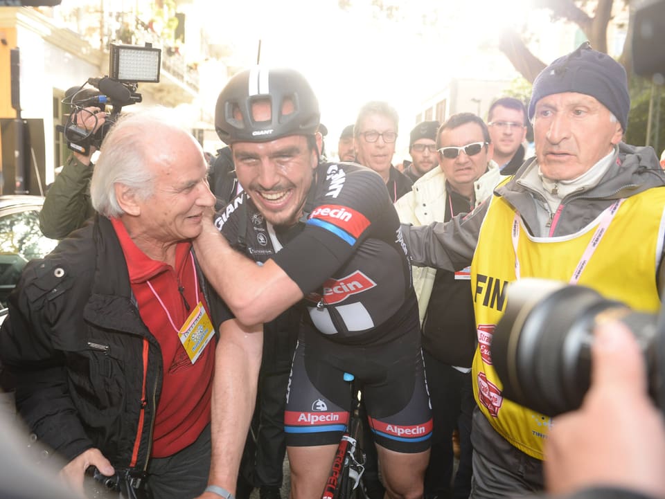 John Degenkolb wird nach dem Sieg bei Mailand - San Remo noch auf dem Fahrrad sitzend von seinen Betreuern in Empfang genommen.
