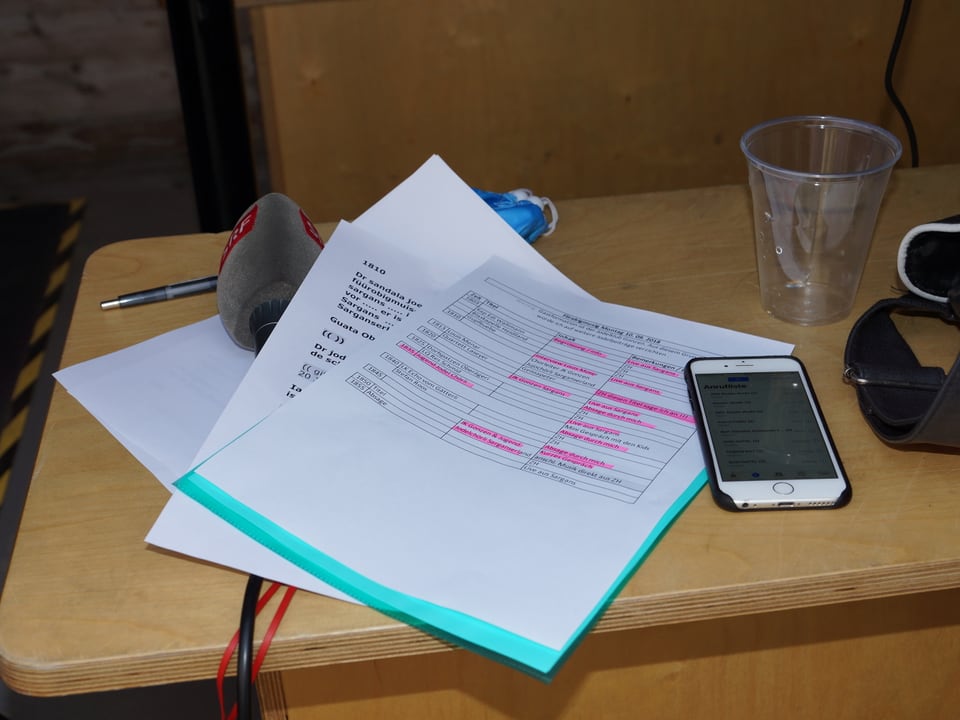 Mikrofon, Manuskript und Smartphone auf einem Tisch.