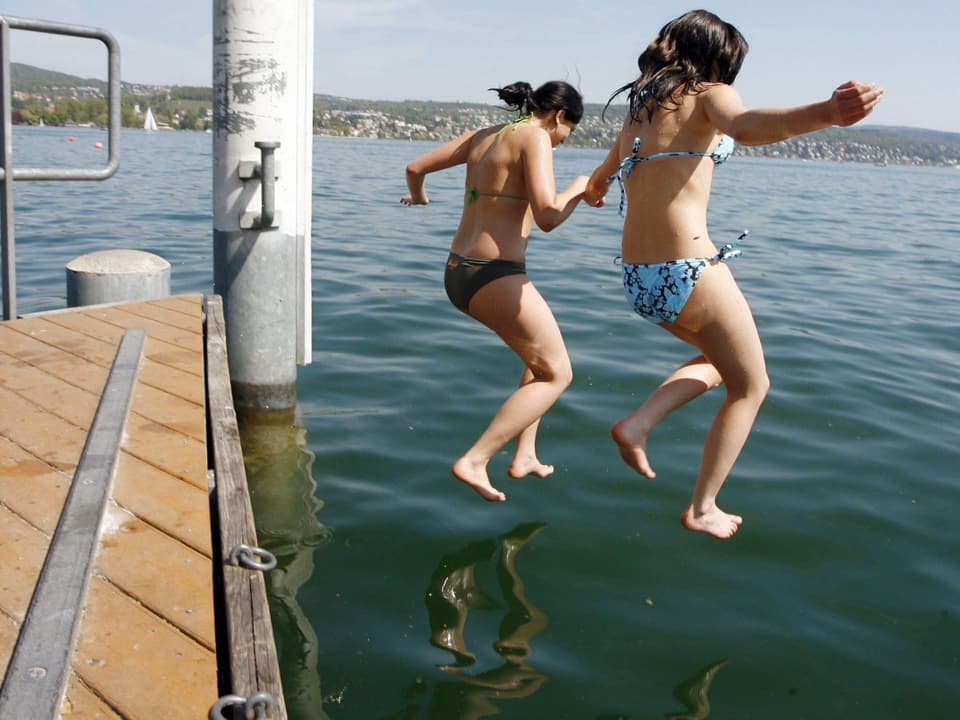 Mädchen springen vom Steeg in den See.