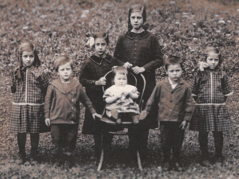 Alte Fotografie mit fünf Mädchen und zwei Buben, die für den Fotografen posieren.