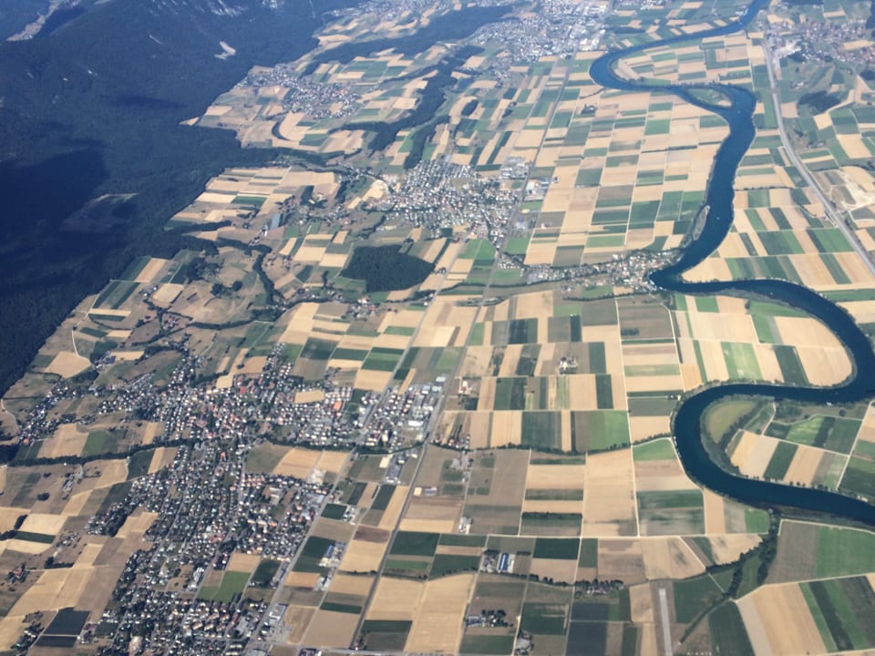 Luftbild auf Landschaft mit hellbraunen Felder und einem Fluss. 