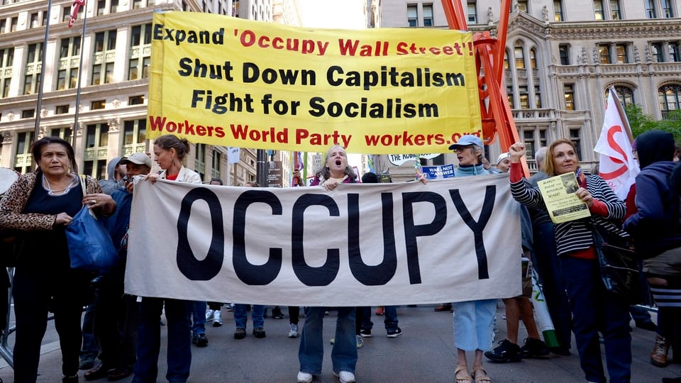 Occupy Wall Street Demonstration mit transparenttragenden Frauen im Vordergrund