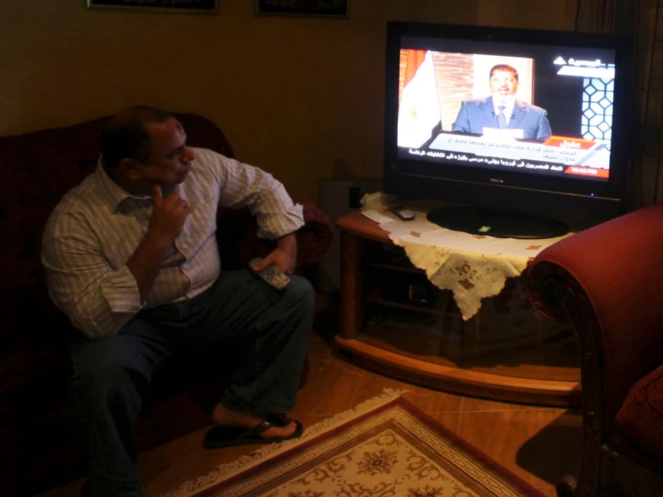 Ein Mann sieht sich im TV einen Auftritt von Mursi an
