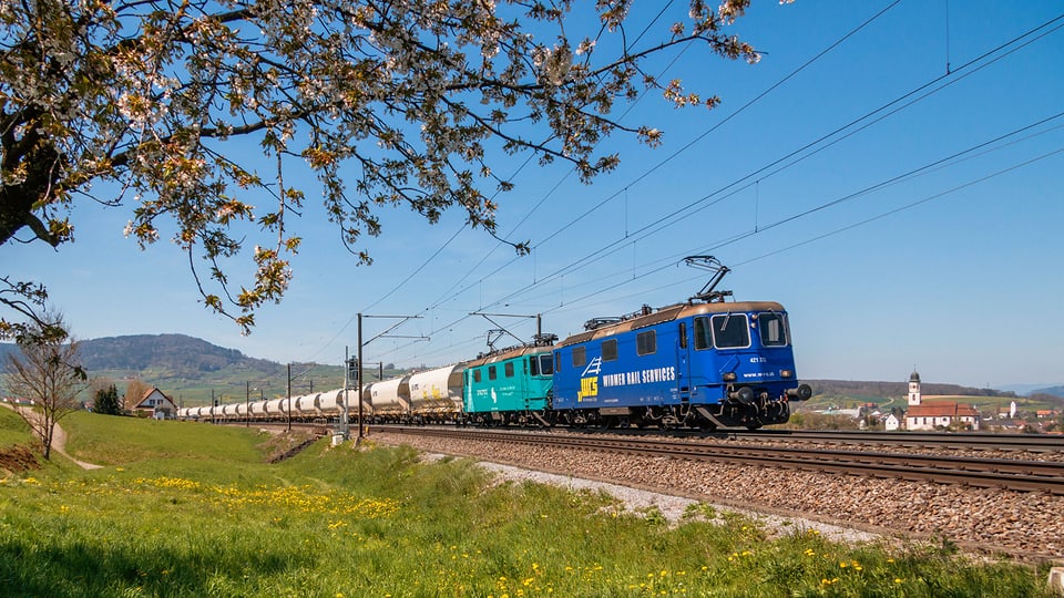 Ein fahrender Zug mit einer blauen Lokomotive.
