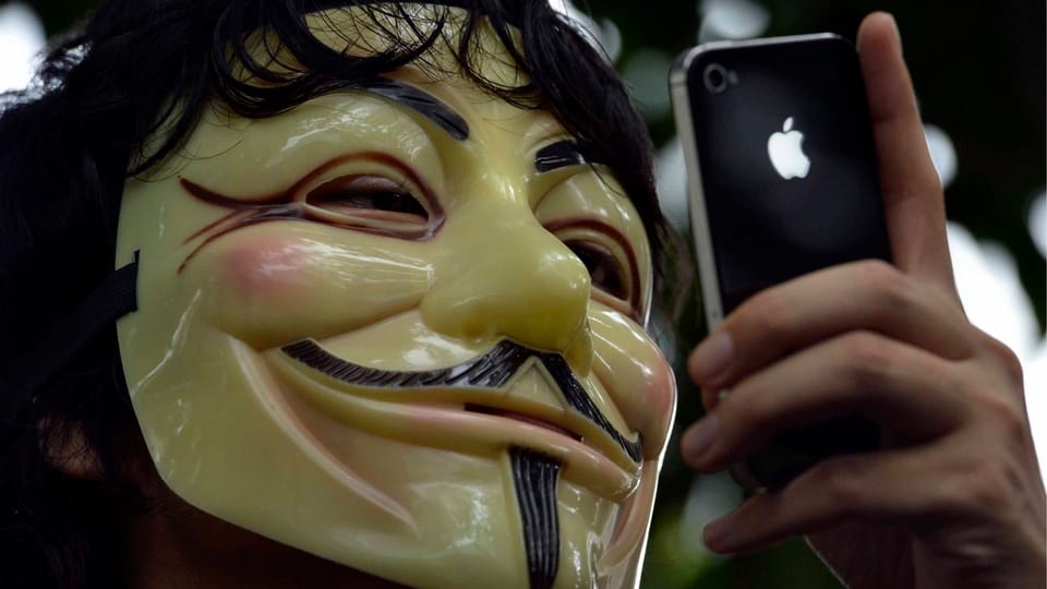 Ein Mann mit Maske hält ein iPhone in der Hand.