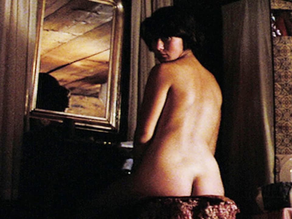 Nackte Frau steht vor einem Spiegel