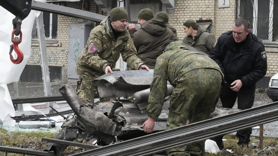 Arbeiter laden in Kiew die Trümmer einer Rakete auf einen Lastwagen.