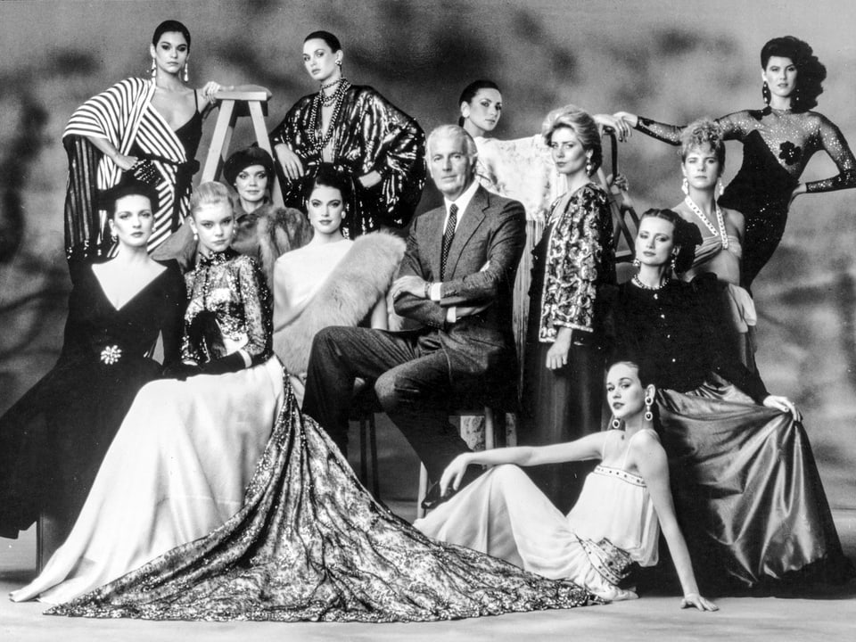 Givenchy in der Mitte einer Gruppe von Frauen in Robe.