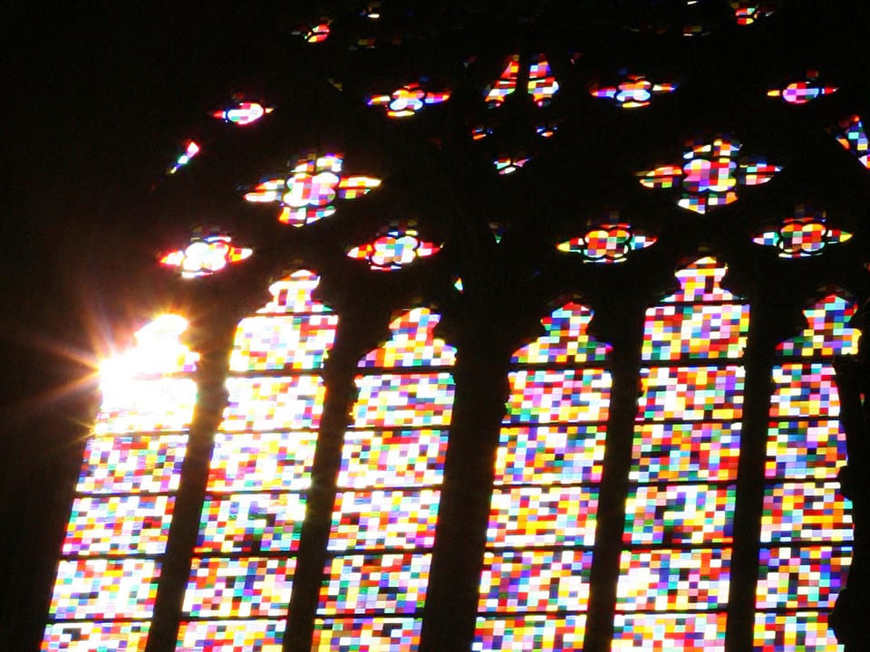 Licht fällt durch die farbigen Riesenfenster einer Kirche.