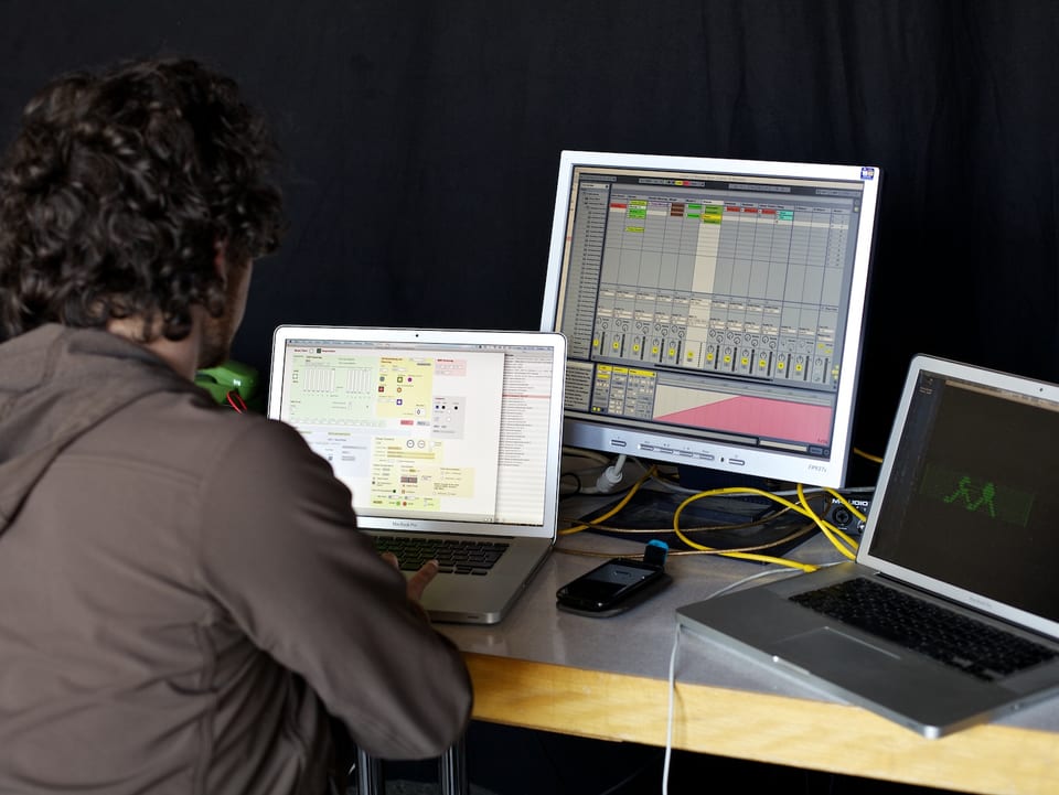 Ein Techniker sitzt vor drei Bildschirmen.