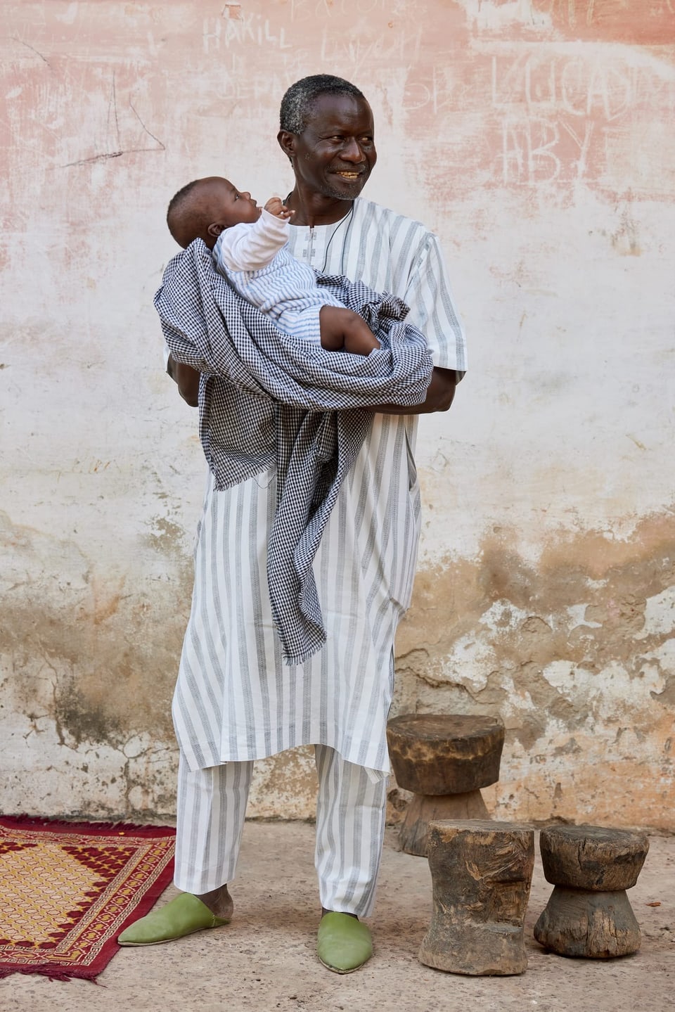 Mann aus Senegal hält ein Kind in den Armen.