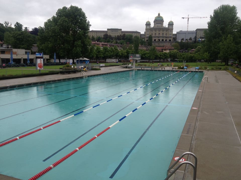 Blick auf ein leeres Schwimmbecken. Im Hintergrund das Bundeshaus.