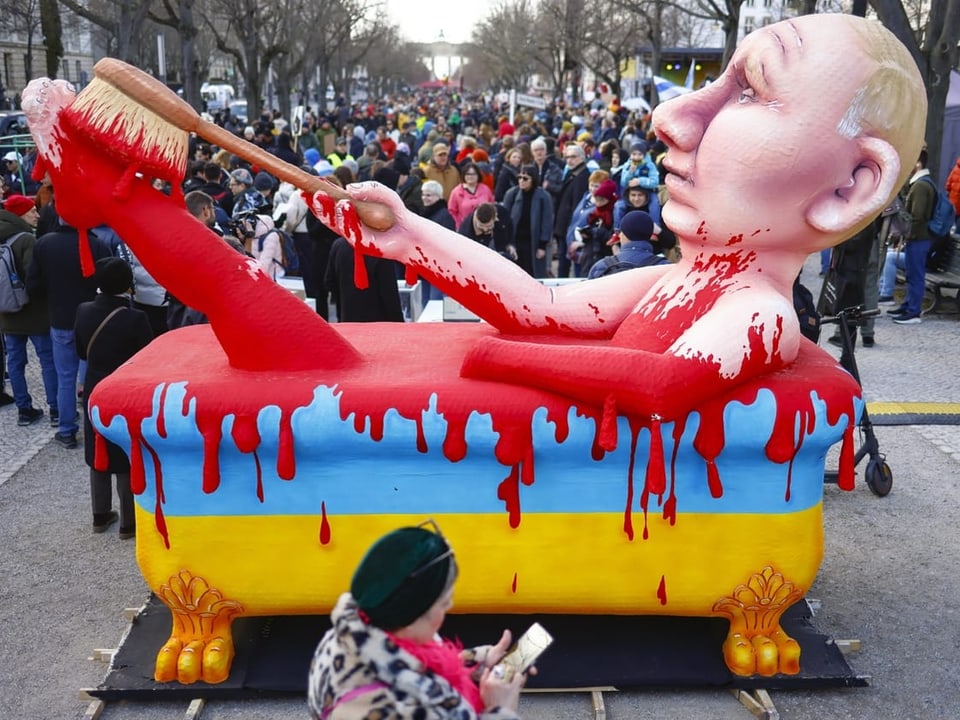 Überlegensgrosse Putin-Papp-Figur in mit ukrainischen Farben und rotem Blut bemalter Badewanne