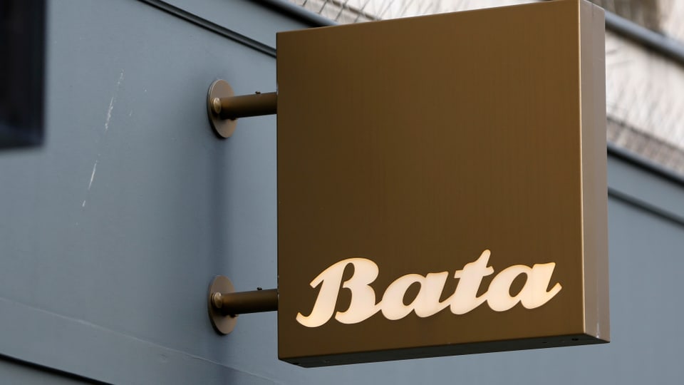 Braunes Schild mit der Aufschrift "Bata" ragt aus einer Hauswand eines Schuhgeschäfts
