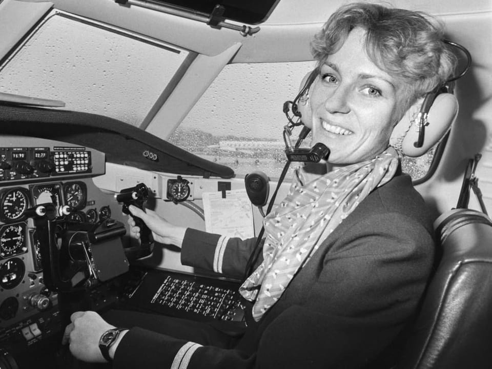 Schwarzweiss Bild, das eine Frau im Cockpit eines Flugzeugs zeigt.