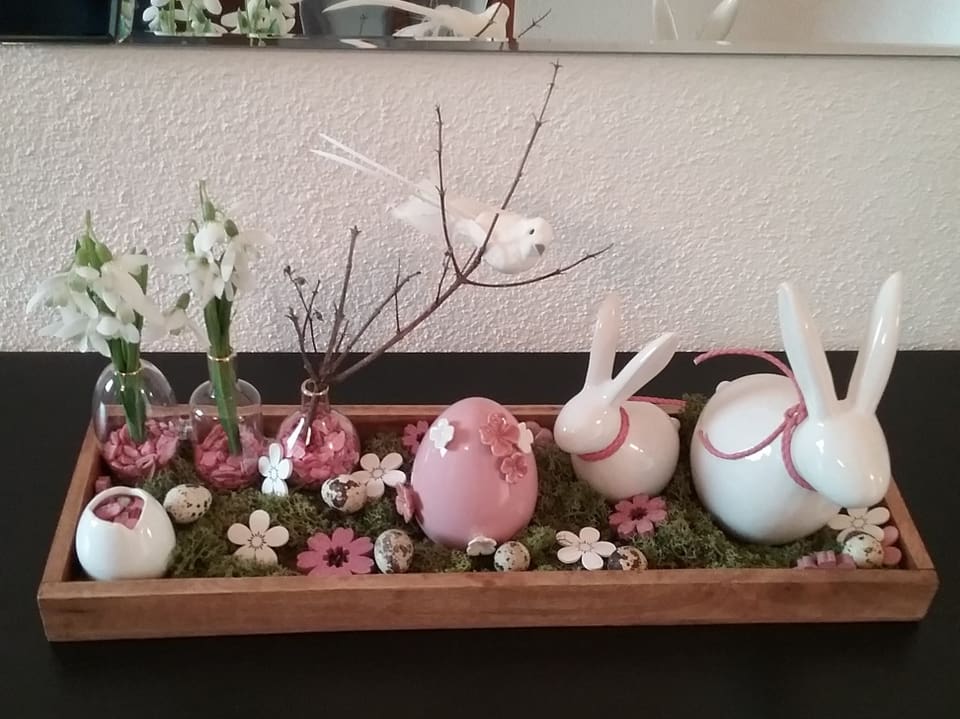 Kleines Arrangement mit weissen und rosafarbenen Osterhasen udn Eiern aus Porzellan. 