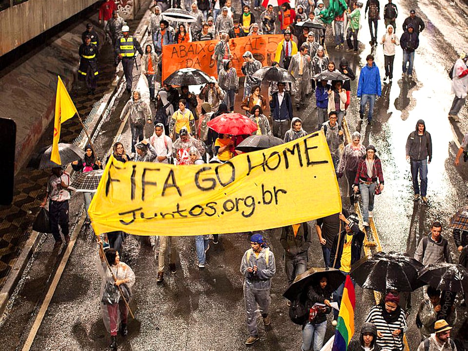 Brasilianer demonstrieren. SIe tragen ein Banner mit der Aufschrift «Fifa go home».