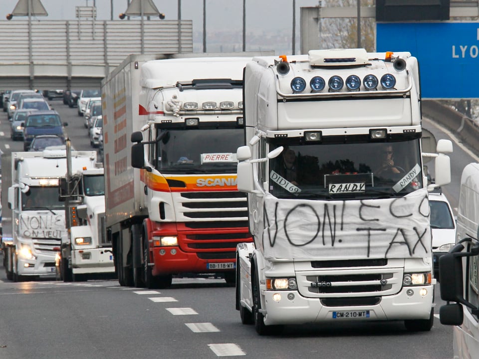 Ein Lastwagen fährt auf der Autobahn mit einem an der Front angebrachten Transparent.