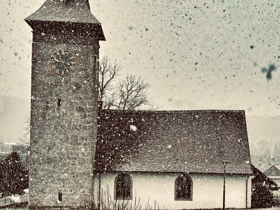 Schnee fällt, man sieht eine Kirche mit Kirchturm
