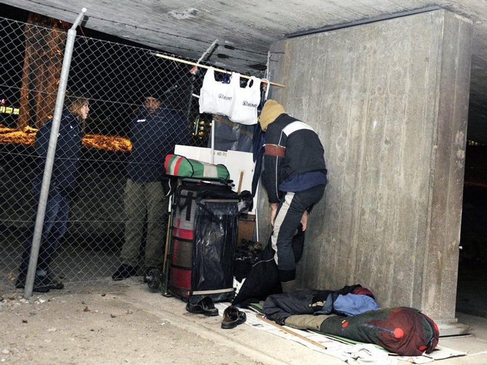 Ein Obdachloser, der sich unter einer Brücke eingerichtet hat, redet mit zwei Mitarbeitern der SIP