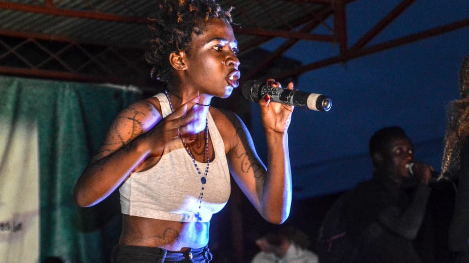 Eine junge schwarze Sängerin auf einer Festivalbühne.