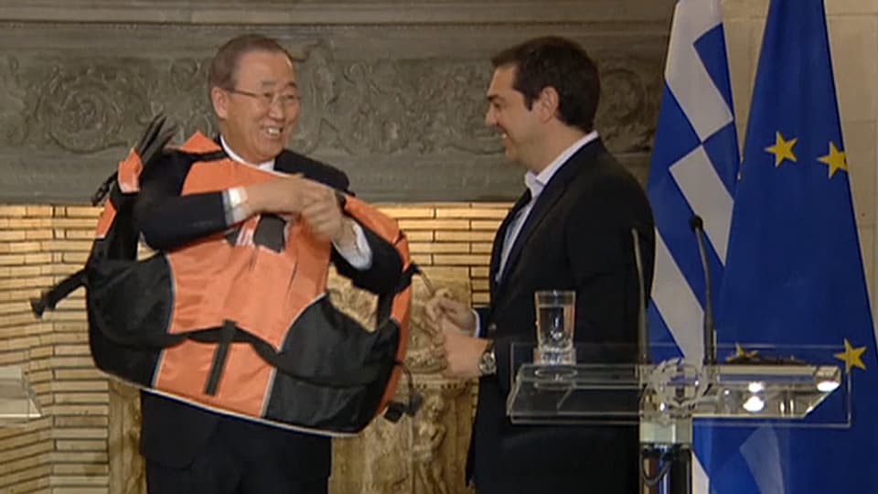 Ban Ki-Moon rudert in der Schwimmweste mit den Armen, Alexis Tsipras grinst dazu.