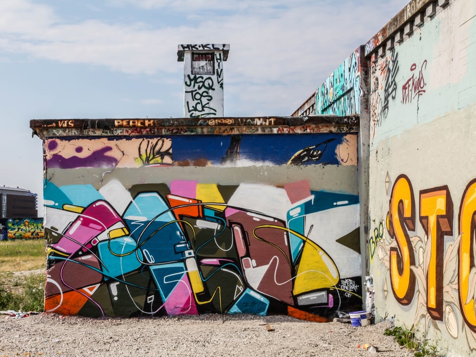 Ein farbiges Graffiti von Pase an einer Fabrikwand.