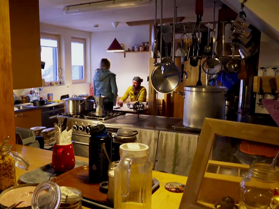 vollgestellte Küche, im Hintergrund Stewart und Perreten am Tisch