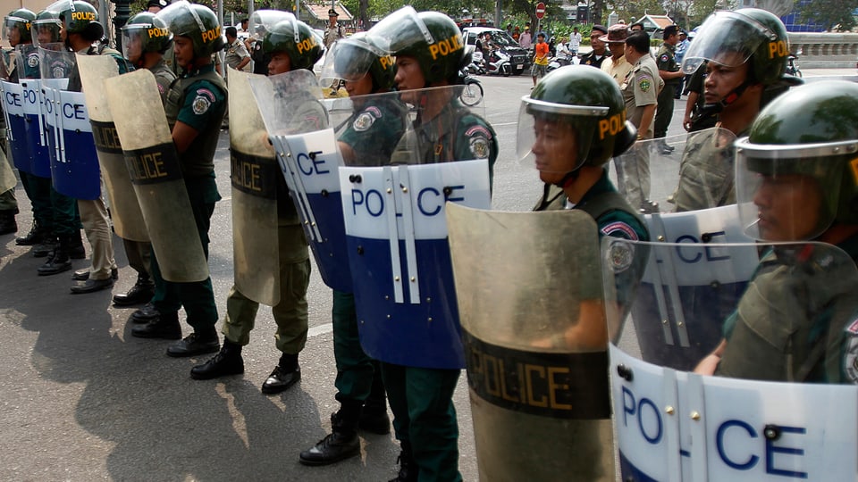 Kambodschaniesche Polizisten stehen mit Schild und Helm in einer Reihe.