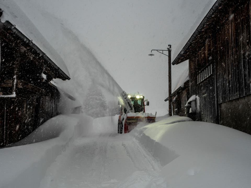 Schneeschleider auf Strasse, die meterhoch eingeschneit ist