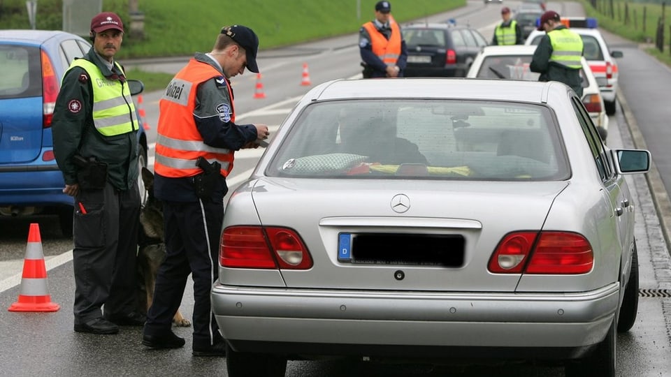 Grenzwächter und Polizisten in Leuchtwesten kontrollieren Autos. 
