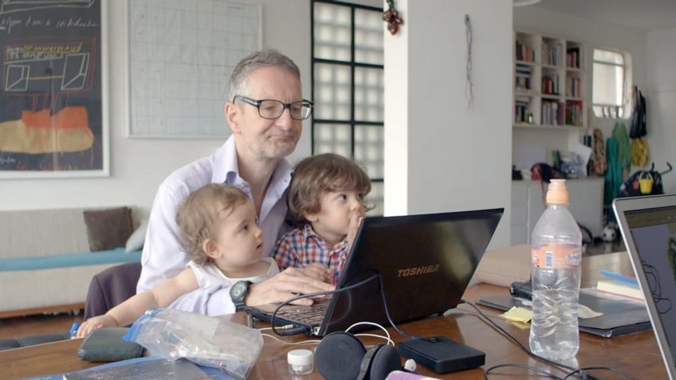 Der zweifache Vater Thomas Haemmerli tippt mit seinen Kids auf dem Schoss etwas in seinen Laptop.